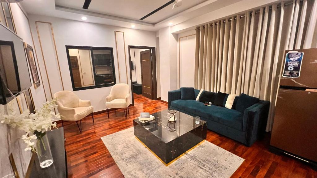 a living room with a blue couch and a table at Grand Atrium Designer Apartment in Faisalabad