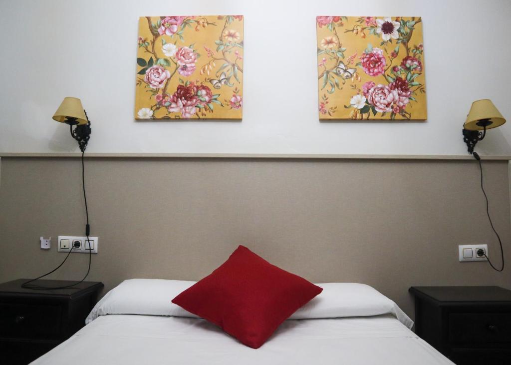 a bedroom with two beds and three paintings on the wall at Apartamentos Turisticos Casa Cantillo in Carmona