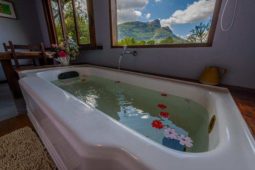 a bath tub filled with water with flowers in it at Pousada Mandala das Águas in Aiuruoca