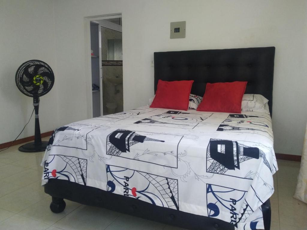 a bed with a black and white comforter and red pillows at Apartamento oasis del norte in Cali