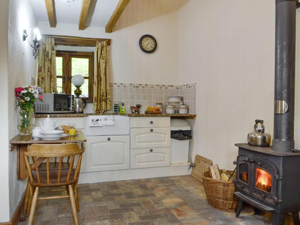 a kitchen with a stove and a table in it at The Cow Shed in Llanfair-ar-y-bryn