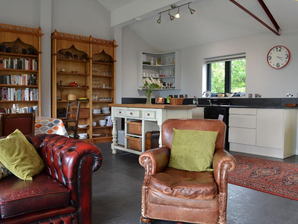 a living room with two leather chairs and a kitchen at Juniper Barn in Westward