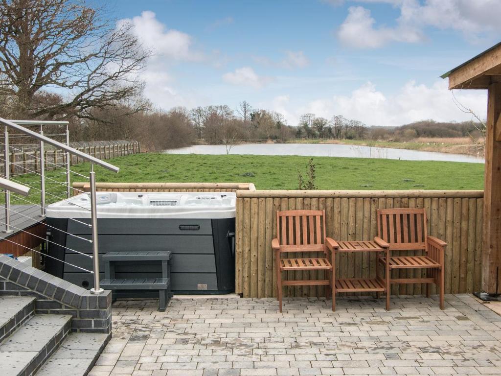 a patio with two chairs and a stove and a fence at Sunnyside Lodge in Glastonbury