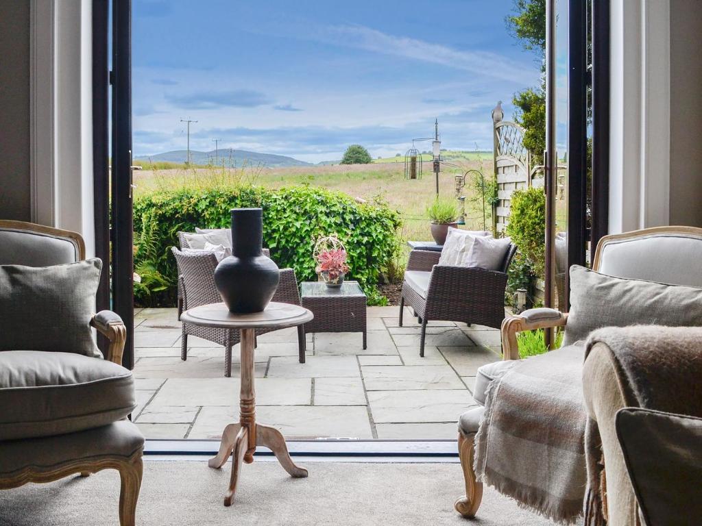 a patio with chairs and a vase on a table at Woodend in Maxwelltown