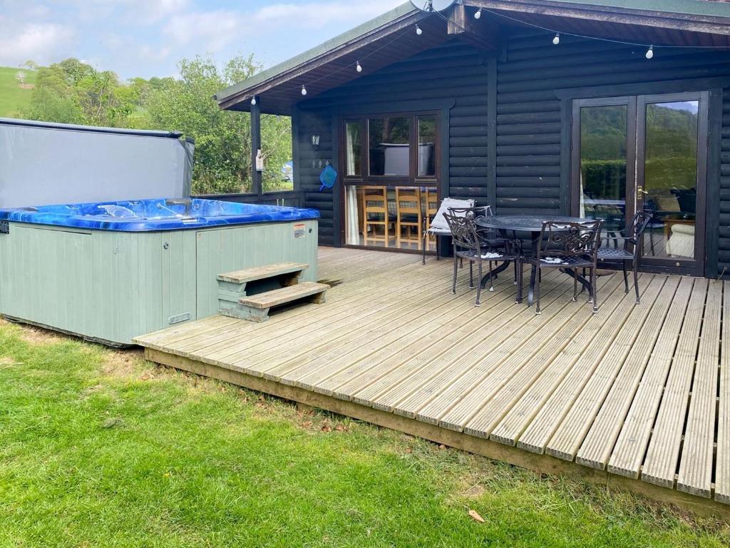 a deck with a hot tub and a table and chairs at Edw Lodge in Aberedw