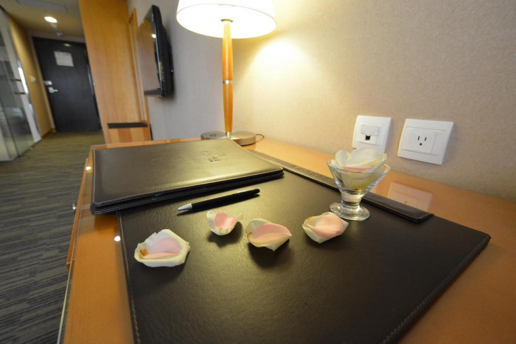 a table with a laptop and a glass on it at Fushin Hotel Taichung in Taichung