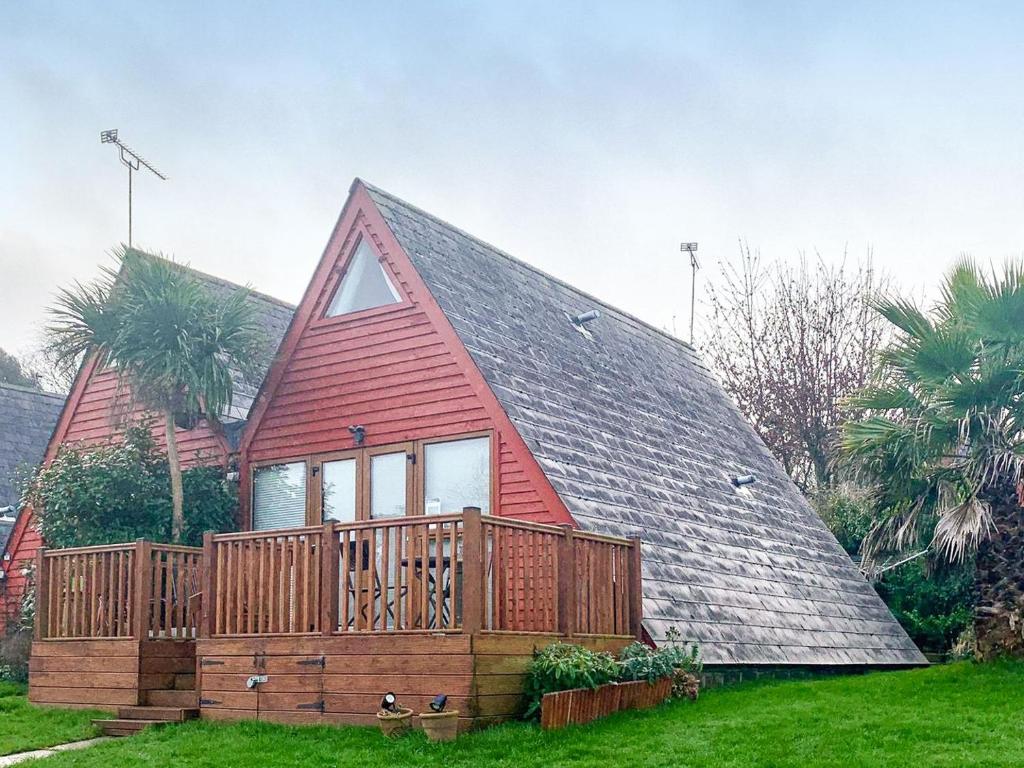 a large red house with a deck on a lawn at Poppy Lodge in Kingsdown