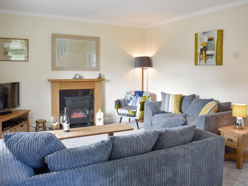 a living room with blue couches and a fireplace at Grassgarth Cottage in Redmire