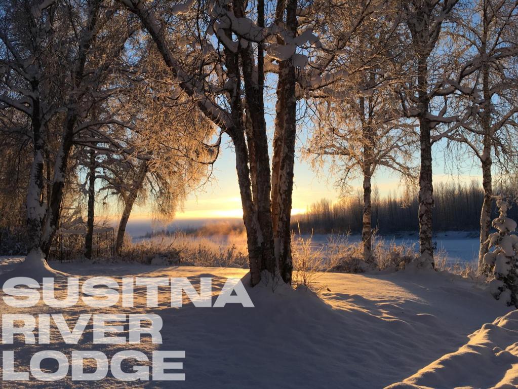 un paesaggio invernale con alberi e le parole gibilterra River Lodge di Susitna River Lodging, Backwoods Cabins a Talkeetna