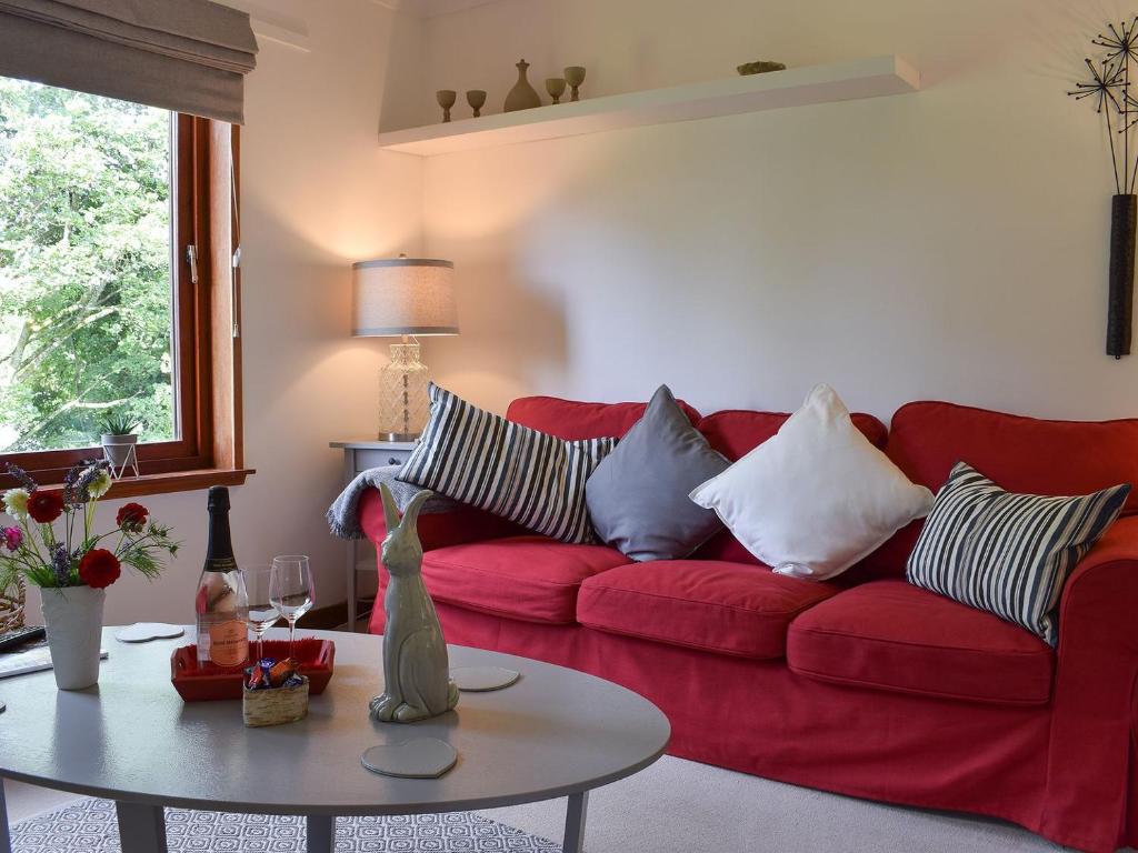 un sofá rojo en una sala de estar con mesa en Tree Tops en Crieff