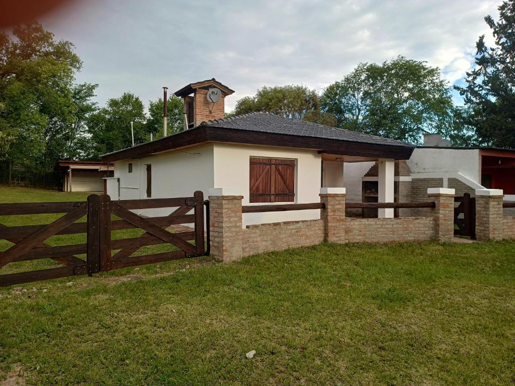 ein kleines Haus mit einem Zaun und einem Glockenturm in der Unterkunft Casita del Río in Santa Rosa de Calamuchita