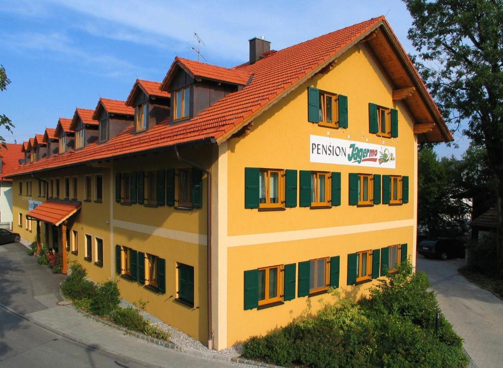 a yellow building with an orange roof at Hotel Jagermo in Grasbrunn