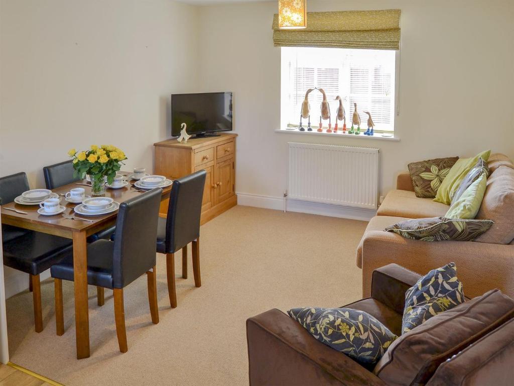 a living room with a table and a couch at Coots Nest in Stalham