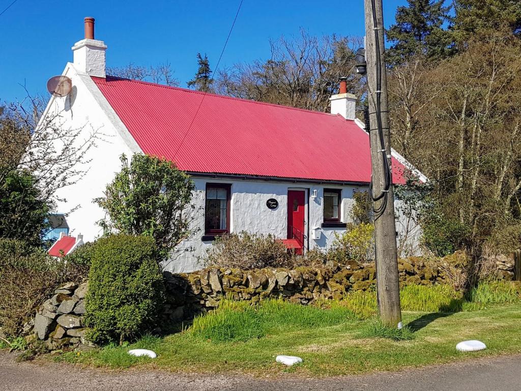 een wit huis met een rood dak en een stenen muur bij Haagwood Cottage in Cretshengan