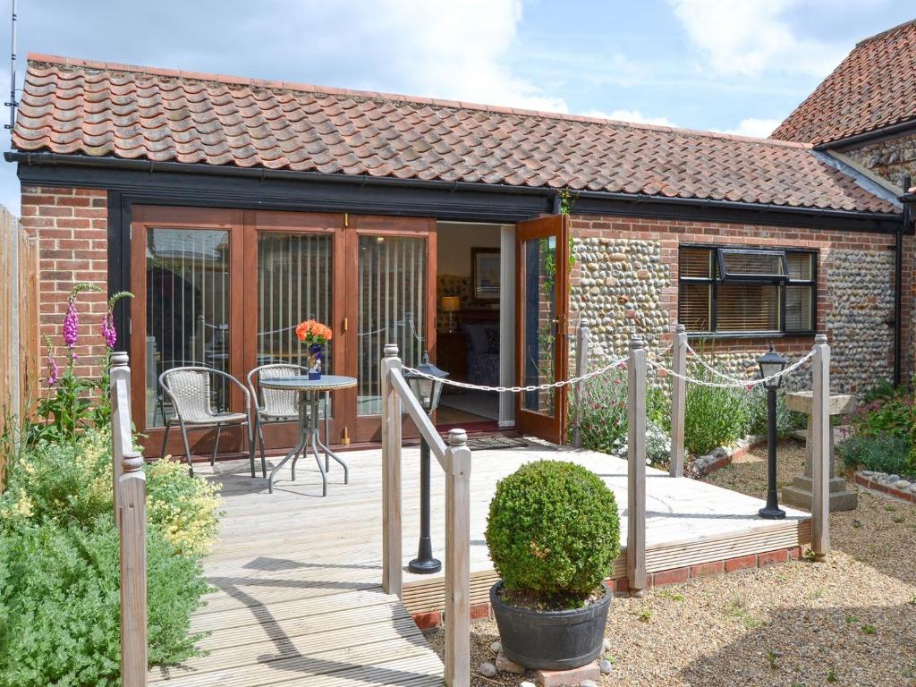 a house with a wooden deck with a table at Courtyard Barn - Uk11927 in Lessingham