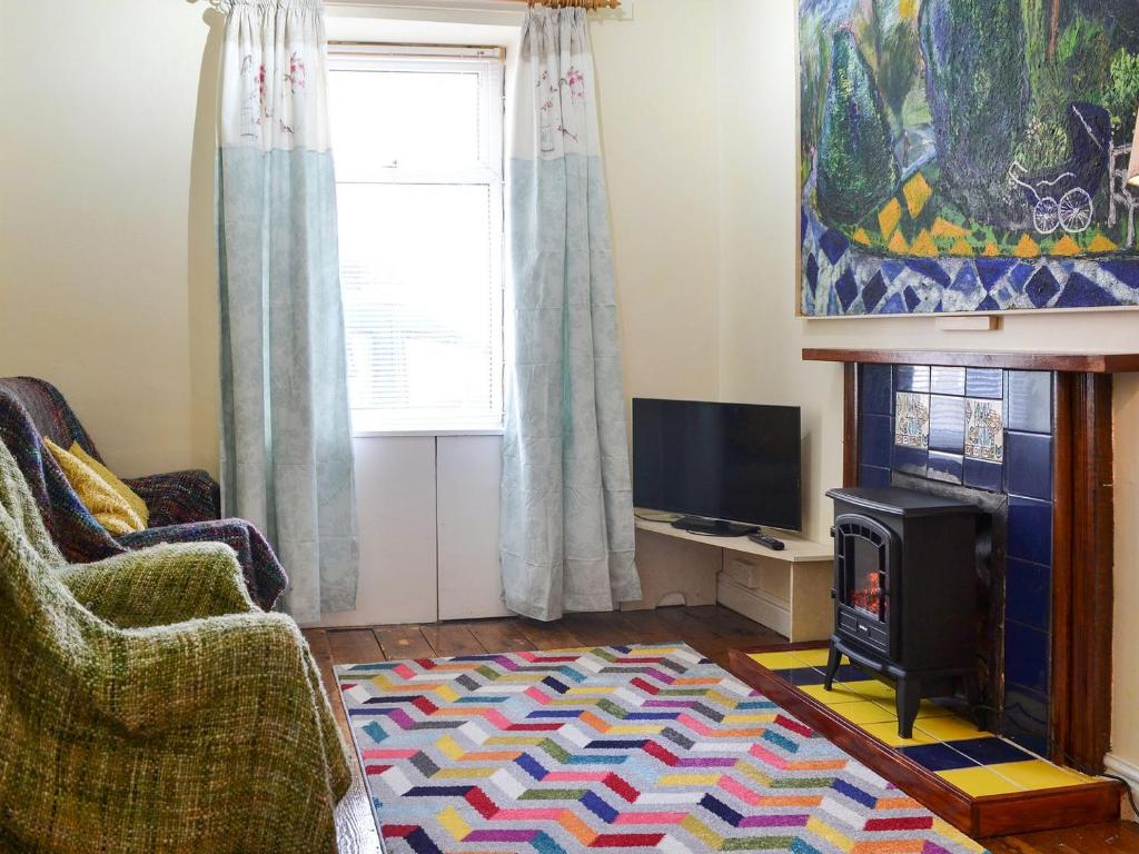 een woonkamer met een open haard en een televisie bij Seagulls in Holyhead