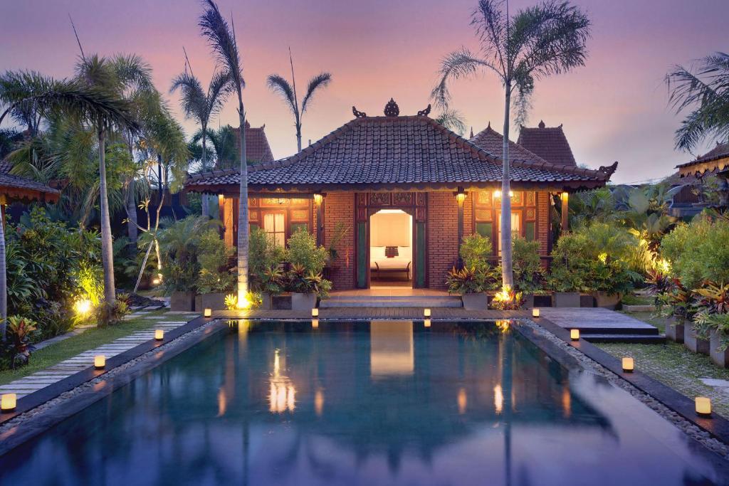 a villa with a swimming pool in front of a house at Villa Berawa in Canggu