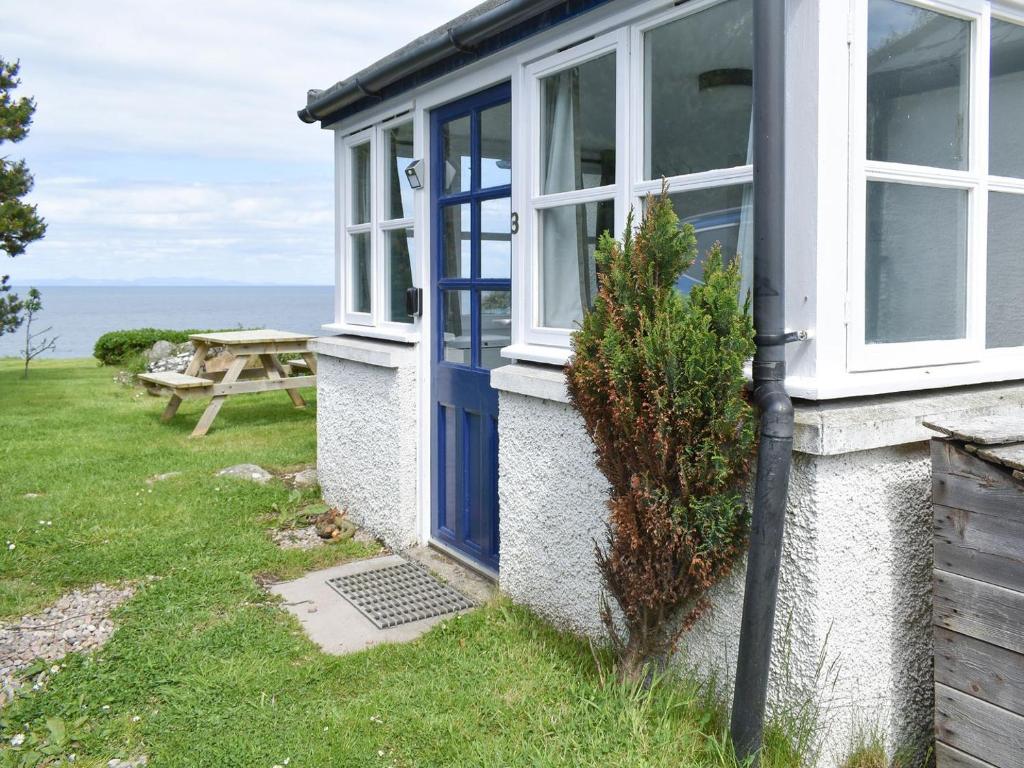 a house with a blue door and a picnic table at 3 Covesea Village in Duffus