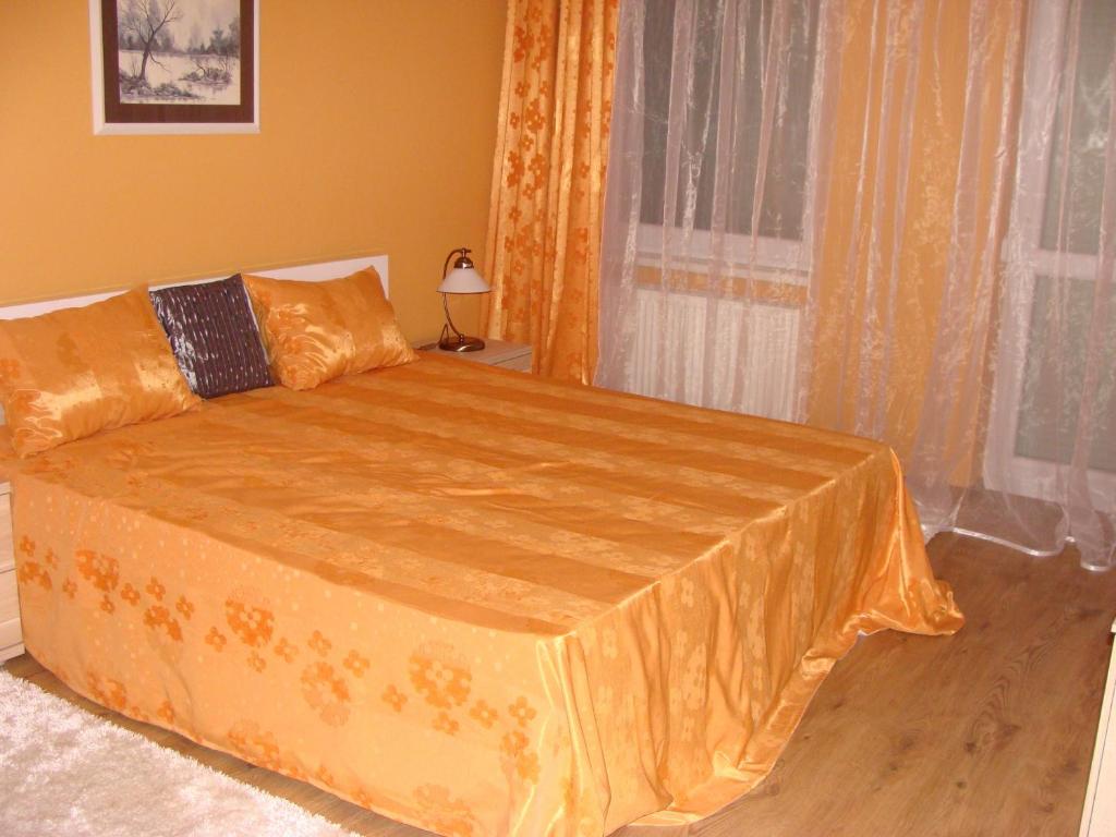 een slaapkamer met een bed met een oranje sprei bij Centrum Business Apartman Szekszárd in Szekszárd