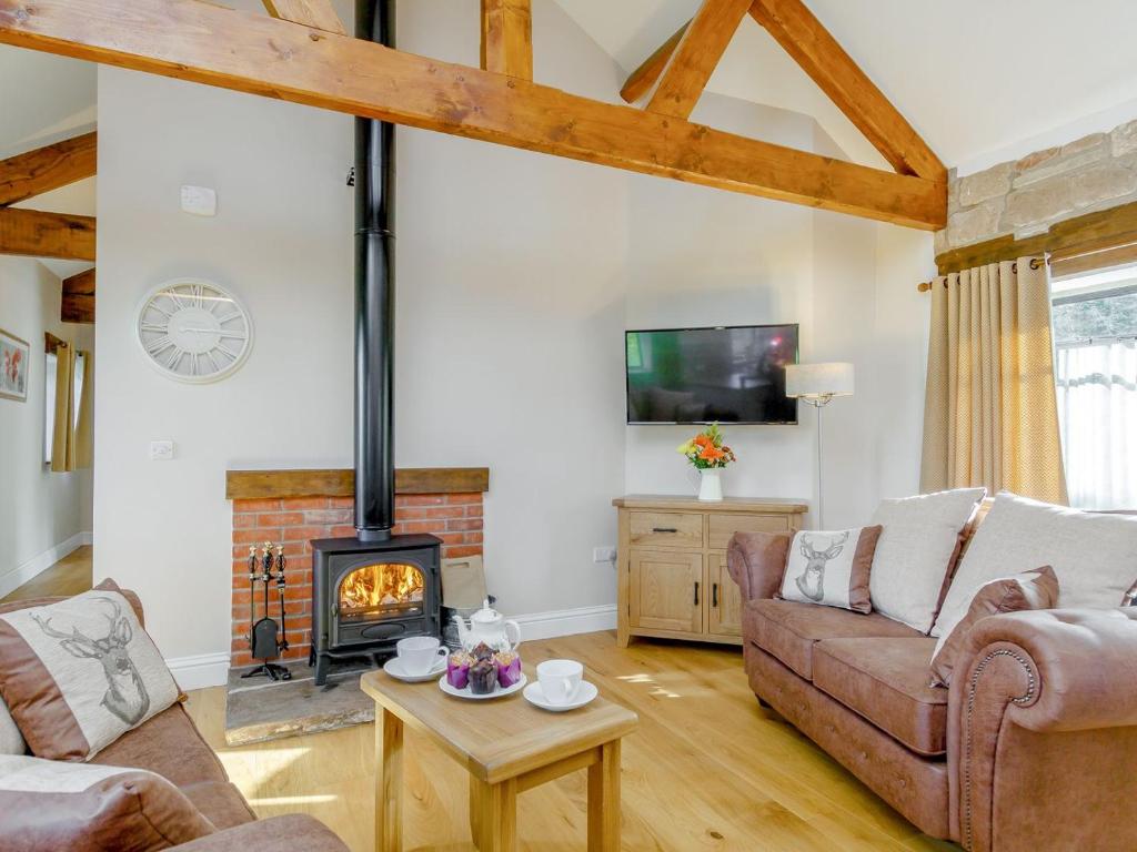 a living room with a couch and a fireplace at The Chicken Coop - Uk12137 in Hewelsfield