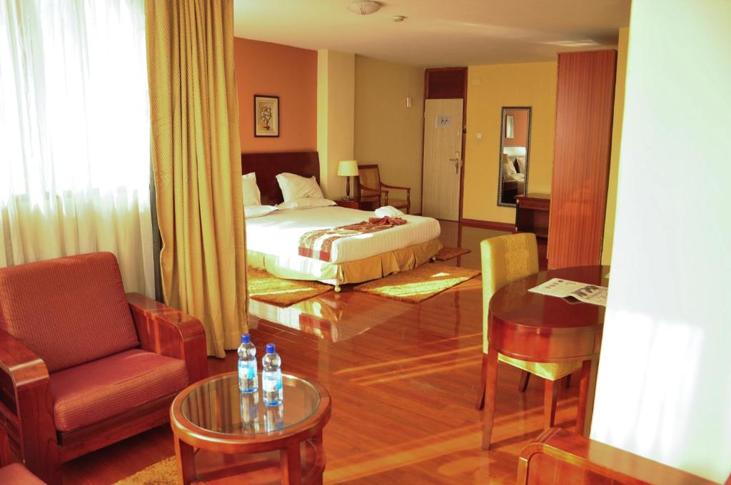 Pokój hotelowy z łóżkiem, krzesłem i stołem w obiekcie Churchill Addis Ababa Hotel w Addis Abebie