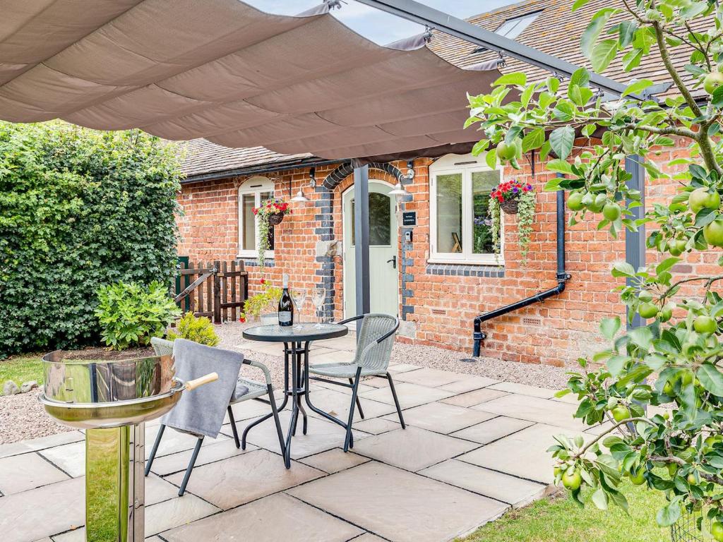 a patio with a table and chairs in front of a brick house at The Parlour - Uk10958 in Burlton