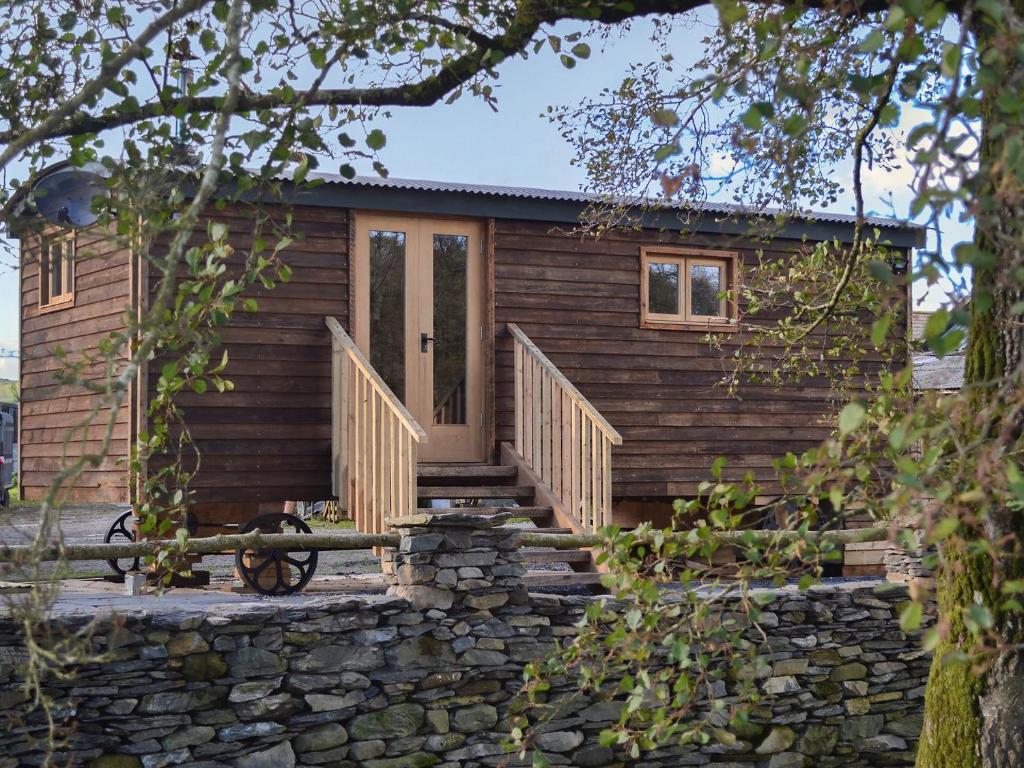 una pequeña casa de madera con una pared de piedra en The Shepherds Hut At Gowan Bank Farm, en Staveley