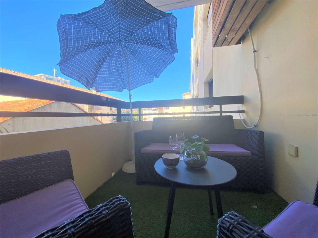 une terrasse avec une table et un parasol bleu dans l'établissement Sainte-Maxime: Appartement 2 pièces rénové avec terrasse, climatisation et à 2 pas de la plage - FR-1-226-498, à Sainte-Maxime