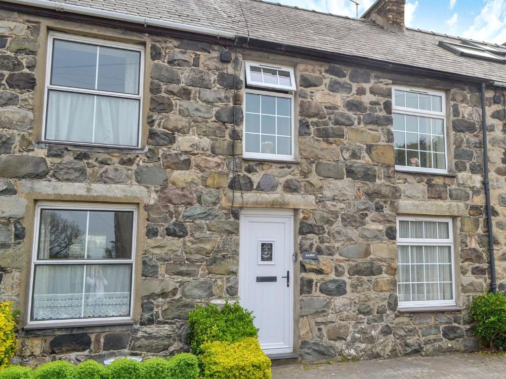 an old stone house with white door and windows at Madryn in Clynnog-fawr