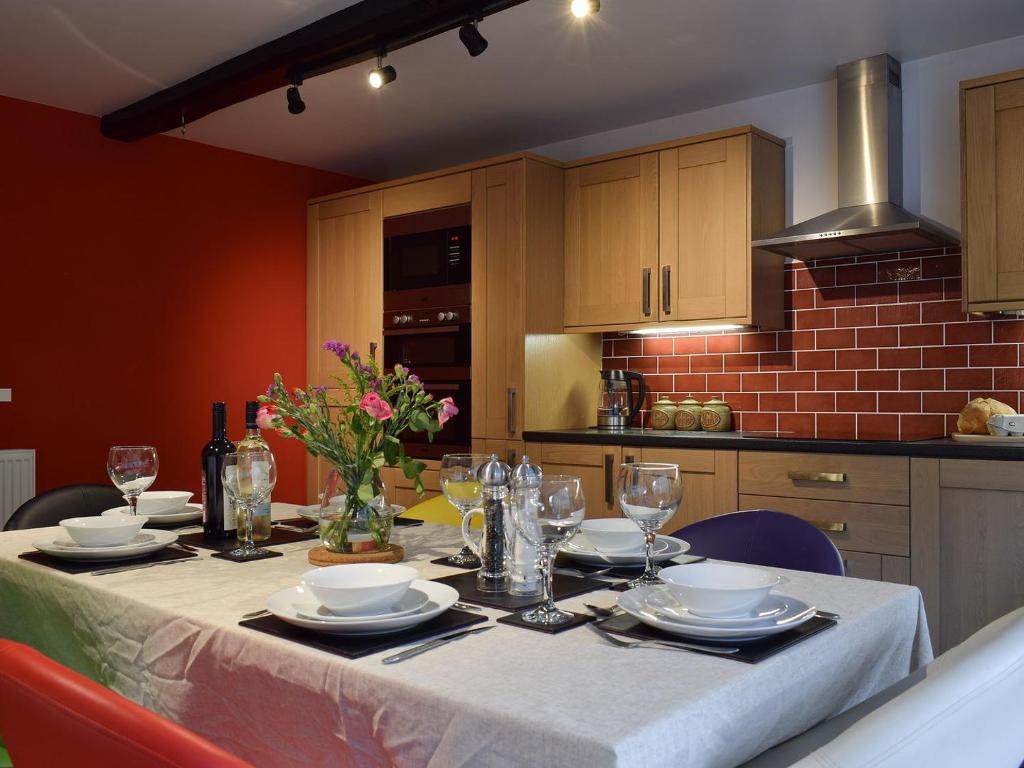 eine Küche mit einem Tisch mit Tellern und Weingläsern in der Unterkunft Barn House in Settle
