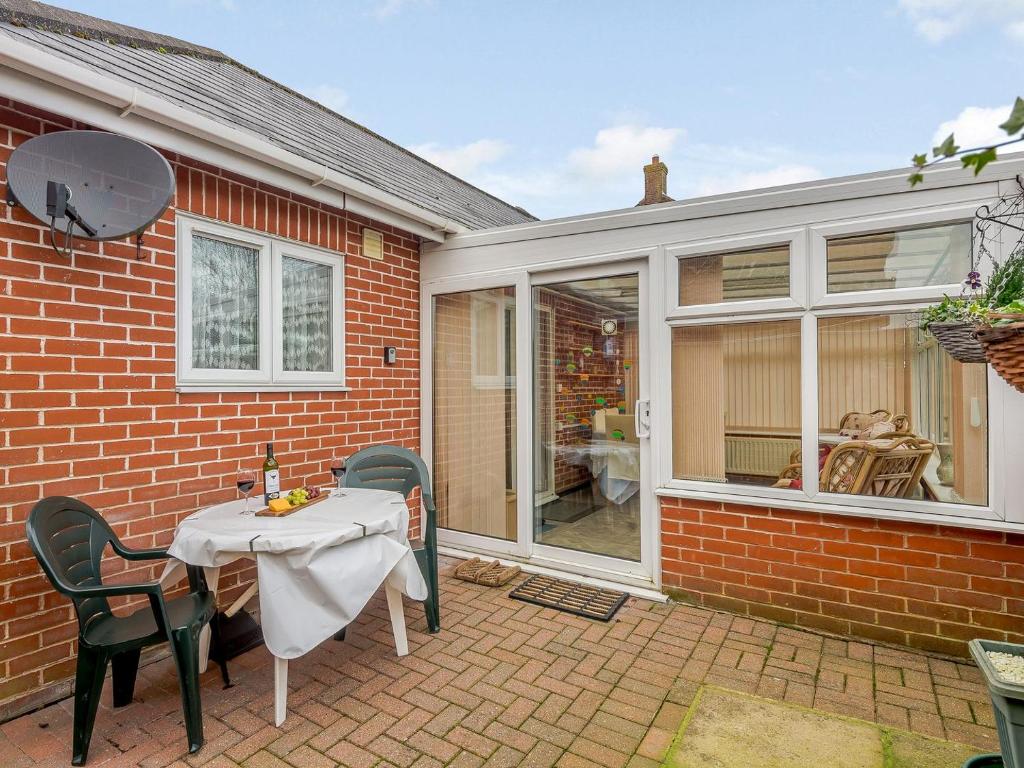 a patio with a table and chairs in front of a house at Fletchers Rest in Cawston