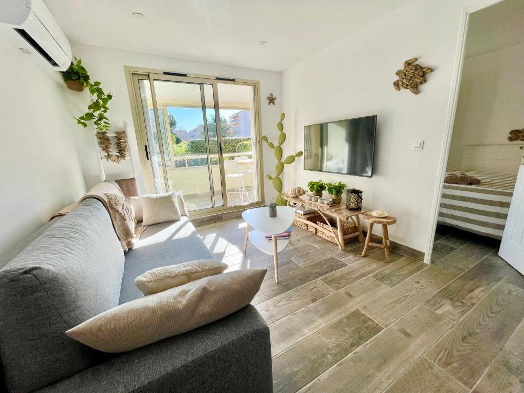 un salon avec un canapé et une table dans l'établissement Perle du Sud avec Parking Privé, piscine été dans Résidence calme, à Sainte-Maxime