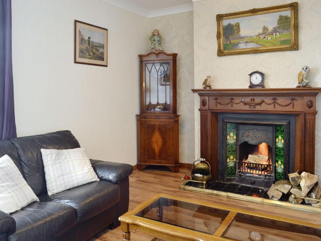 a living room with a couch and a fireplace at Old Stable Cottage in Uplawmoor