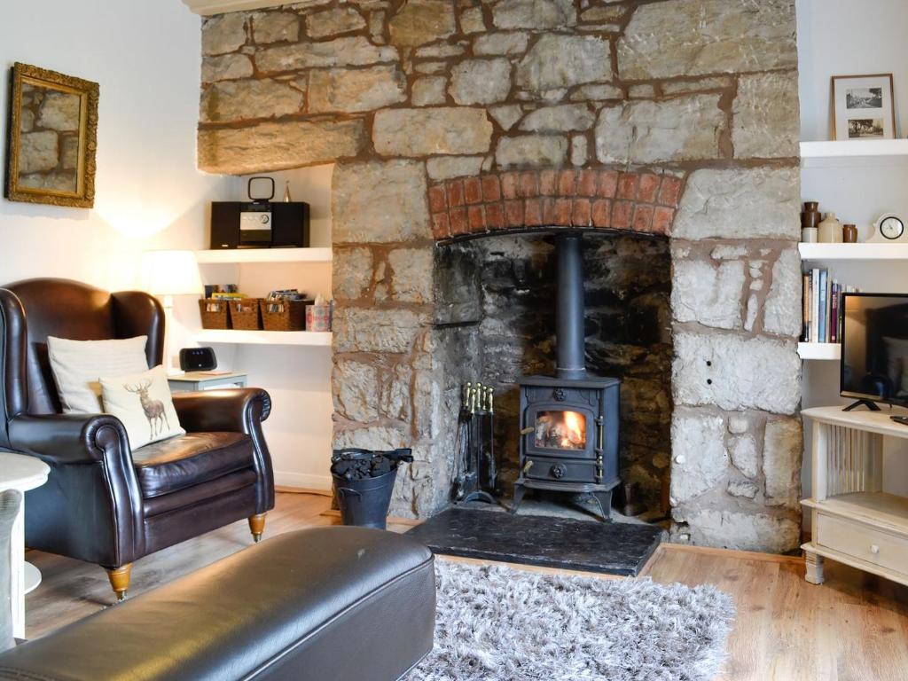 Llandegla的住宿－The Bellringers Cottage，客厅设有石制壁炉、沙发和椅子