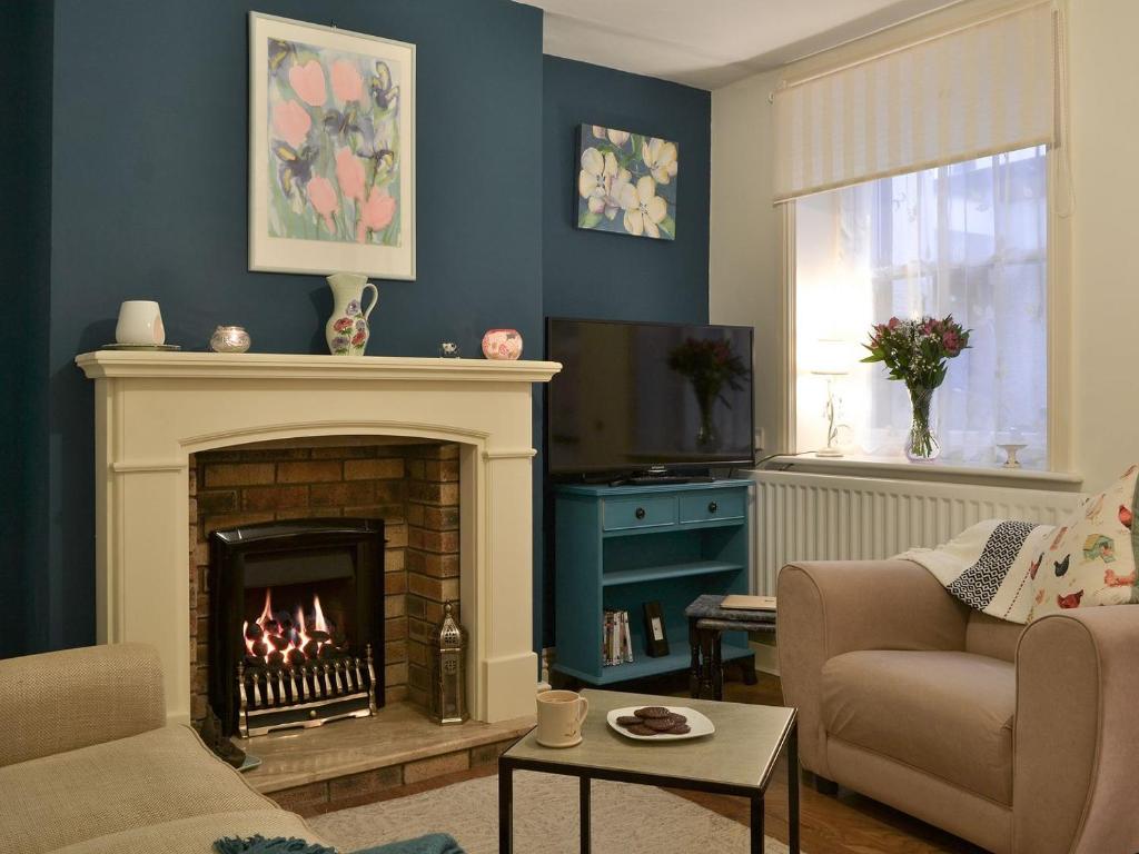 a living room with a fireplace and a couch at Cockleshell Cottage in Cockermouth
