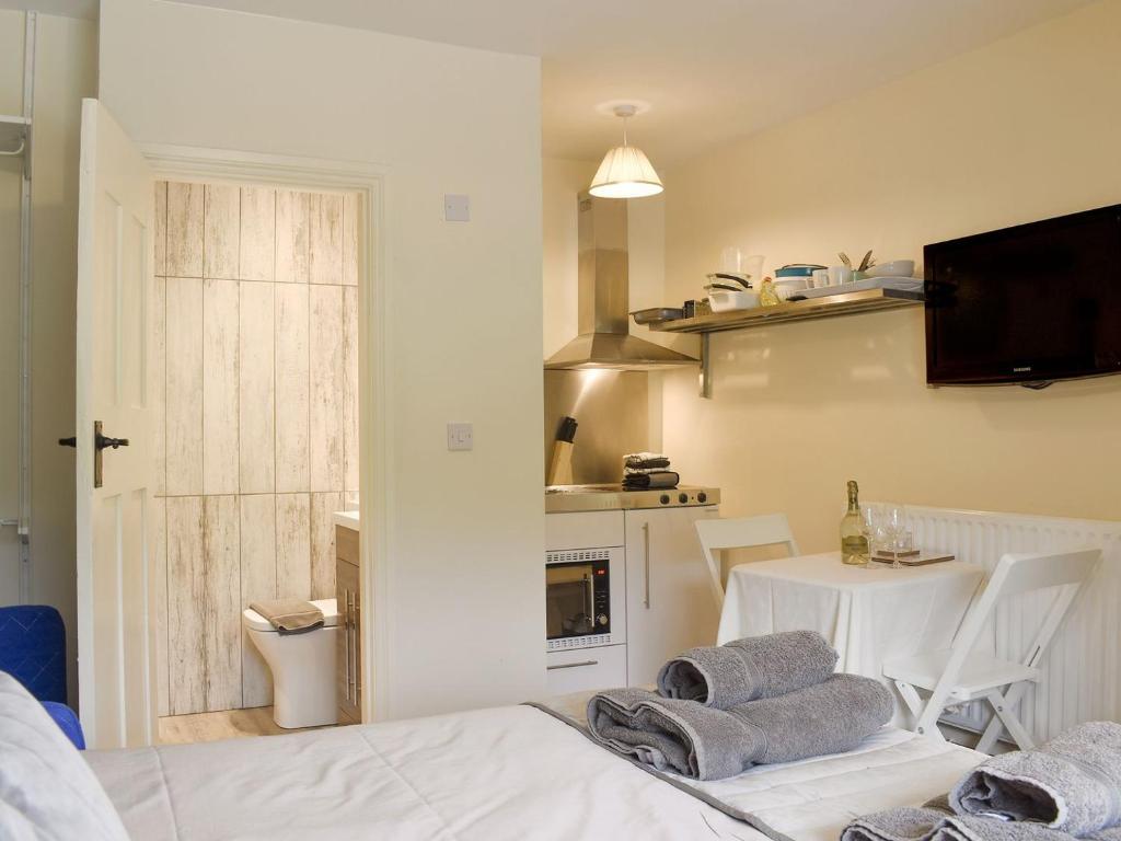 a room with a kitchen and a table with towels on a bed at Court House Mews - Uk11119 in Torver