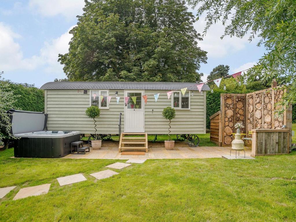 a tiny caravan in a garden with a hot tub at Under Willows - Uk12608 in Burton Overy