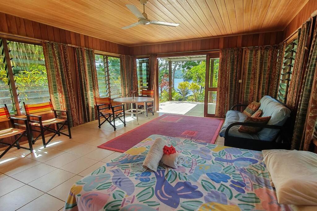 1 dormitorio con 1 cama, mesa y sillas en Aore Hibiscus Retreat, en Aimbuei Bay