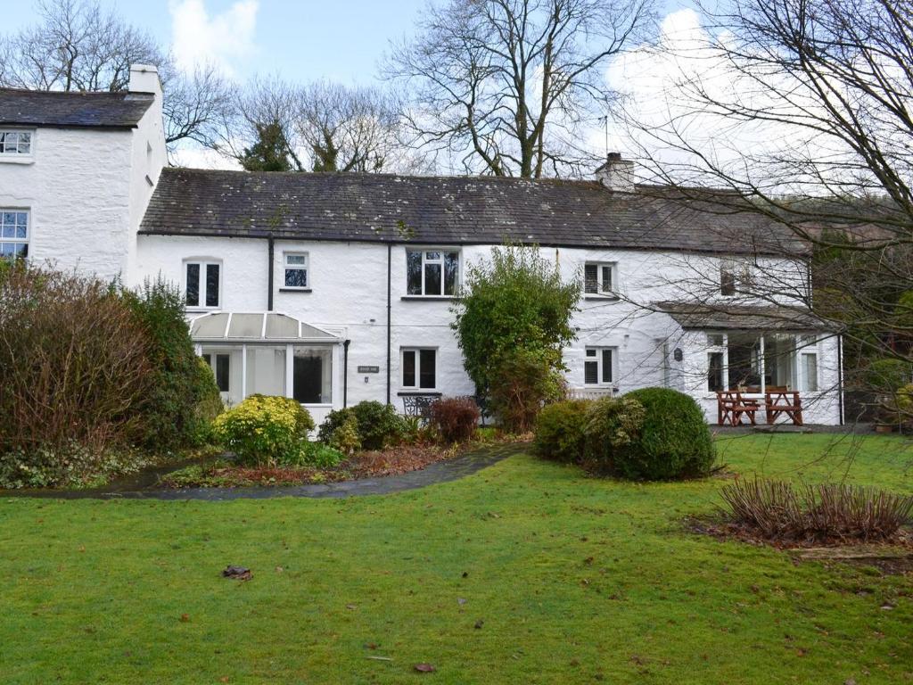 a white house with a yard in front of it at Riverside Cottage in High Nibthwaite