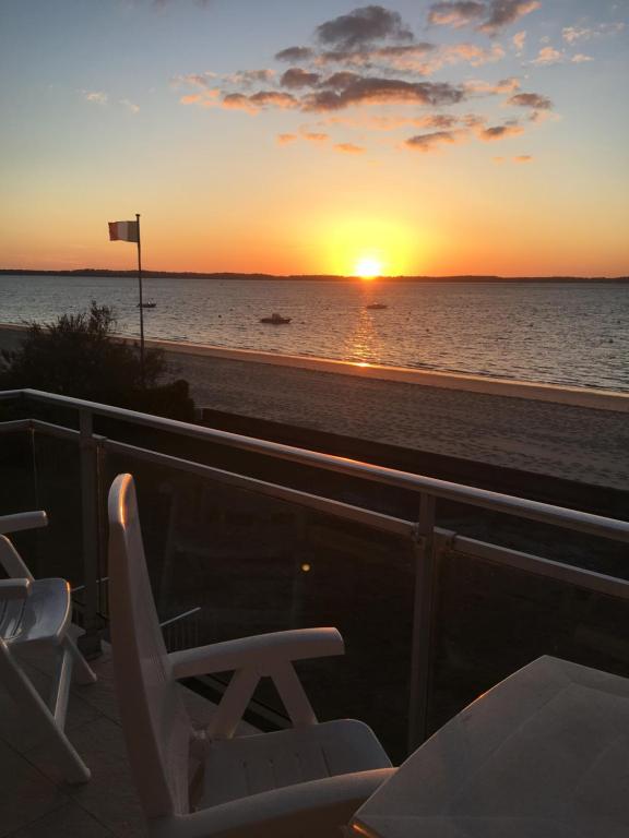 - un coucher de soleil sur la plage avec des chaises sur le balcon dans l'établissement Appartement ARCACHON Perreire Premiere ligne les pieds dans l eau vue magnifique sur le bassin, à Arcachon