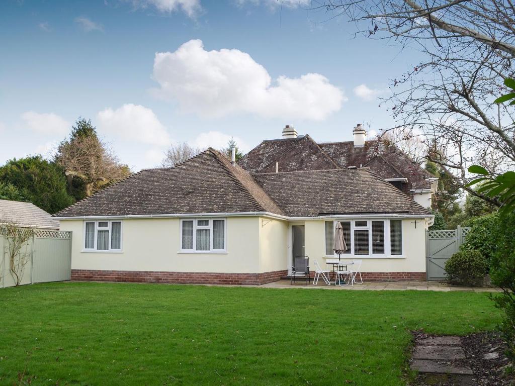 ein weißes Haus mit Rasen davor in der Unterkunft The Cottage At Boscobel in Brockenhurst