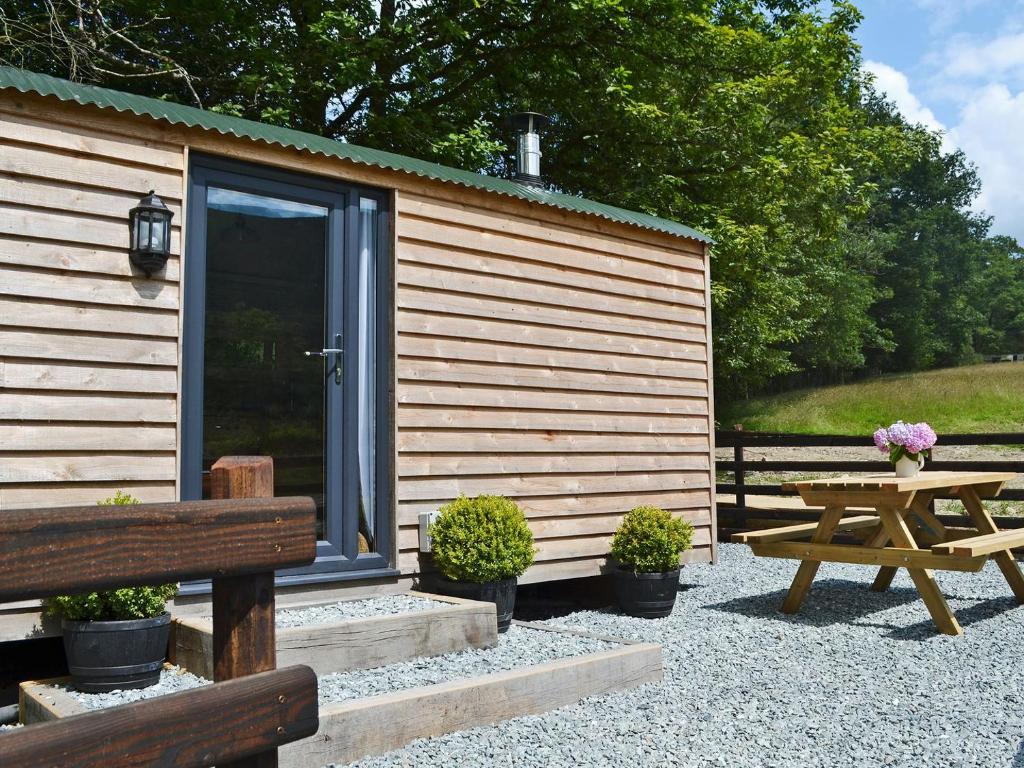 a wooden cabin with a picnic table and a bench at Caban Caru in Dinas Mawddwy