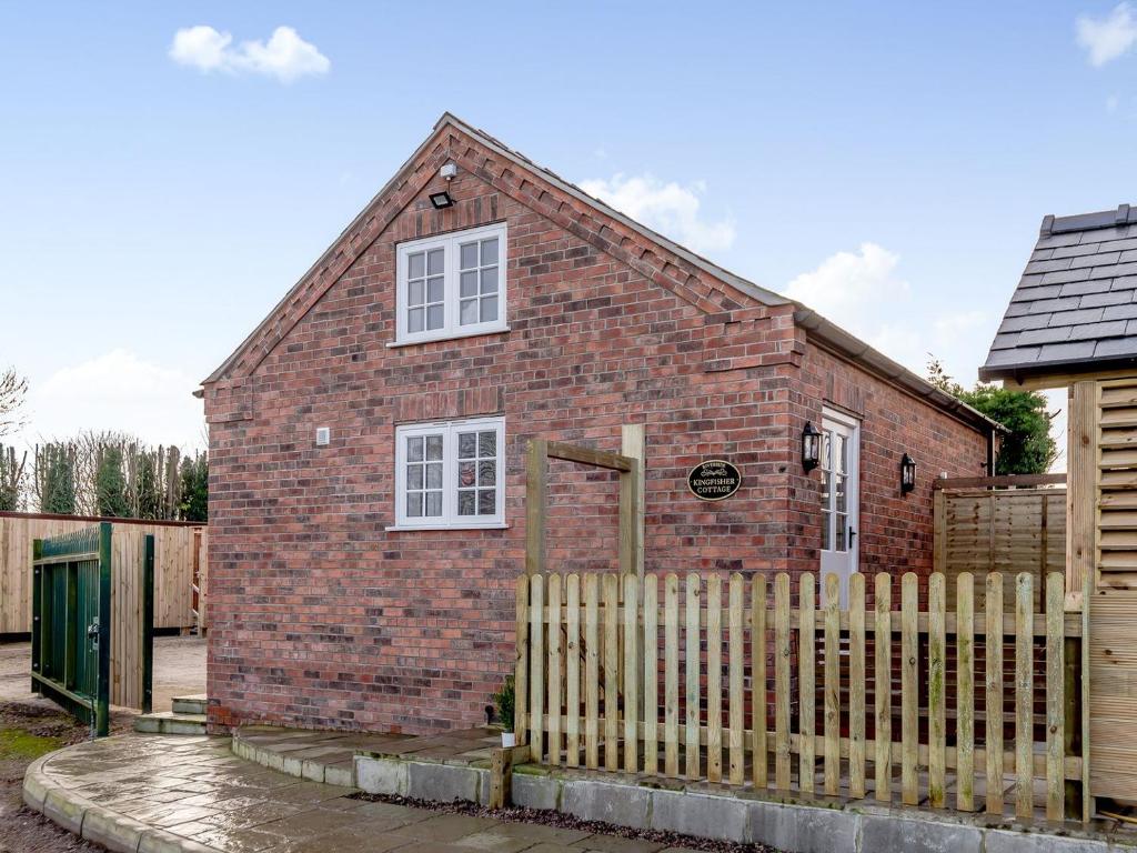 a red brick house with a wooden fence at Kingfisher Cottage in Wainfleet All Saints