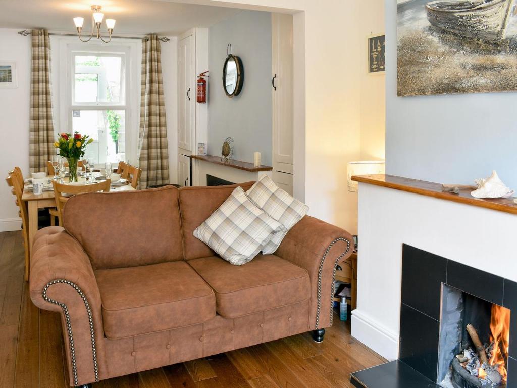 a living room with a couch and a fireplace at Compass Point in Brixham