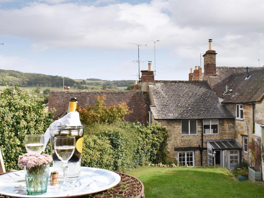 a table with a glass of wine on top of a house at Cenwulf Cottage in Winchcombe