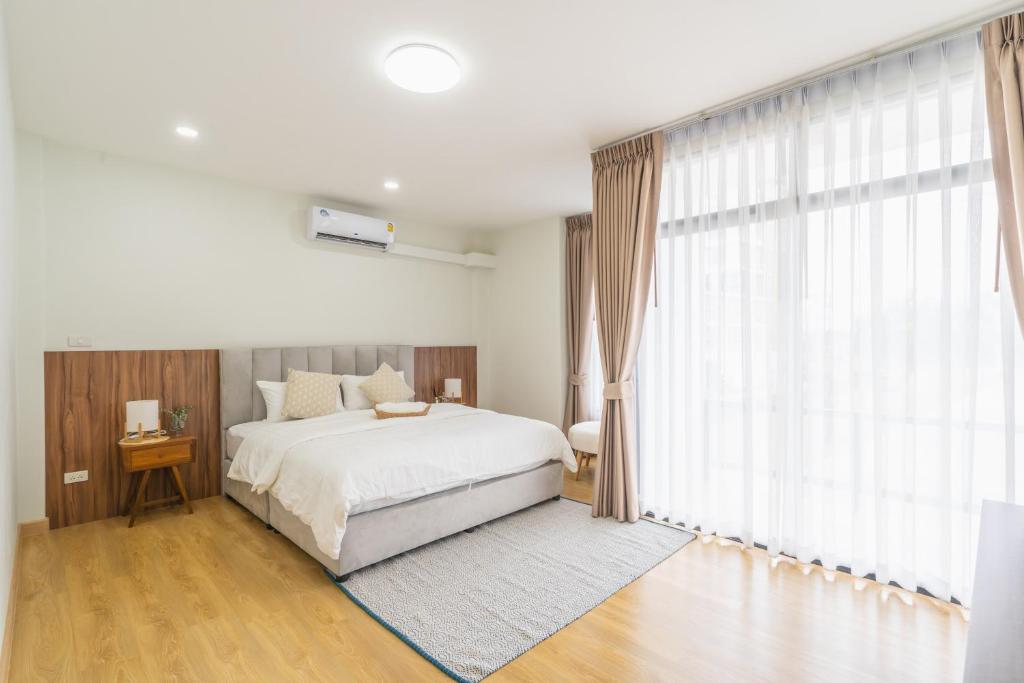 a bedroom with a bed and a large window at The B Hostel in Lamphun
