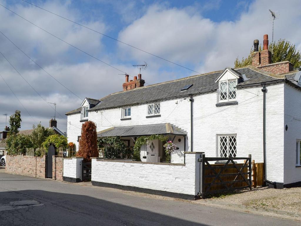 a white house with a gate in front of it at Thwaite Cottage in Sigglesthorne