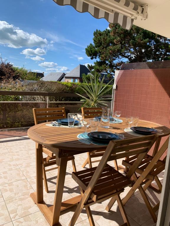 Trouville, appartement rénové avec grande terrasse au calme في تروفيي سور مير: طاولة خشبية عليها أكواب على الفناء