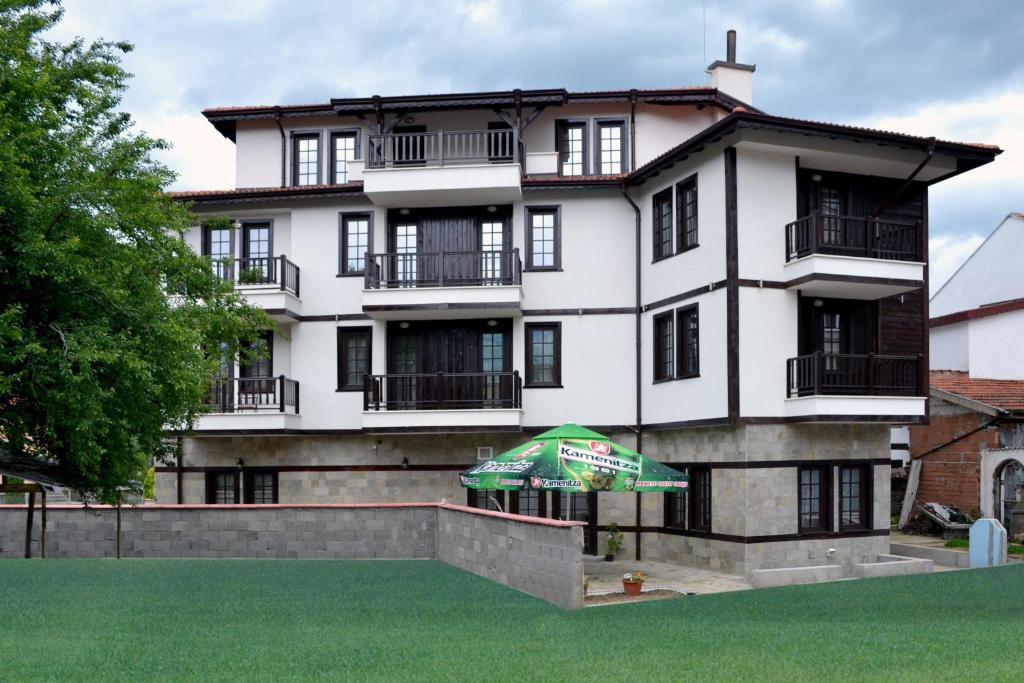 un bâtiment blanc avec un parasol vert devant lui dans l'établissement Krasteva House, à Berkovitsa