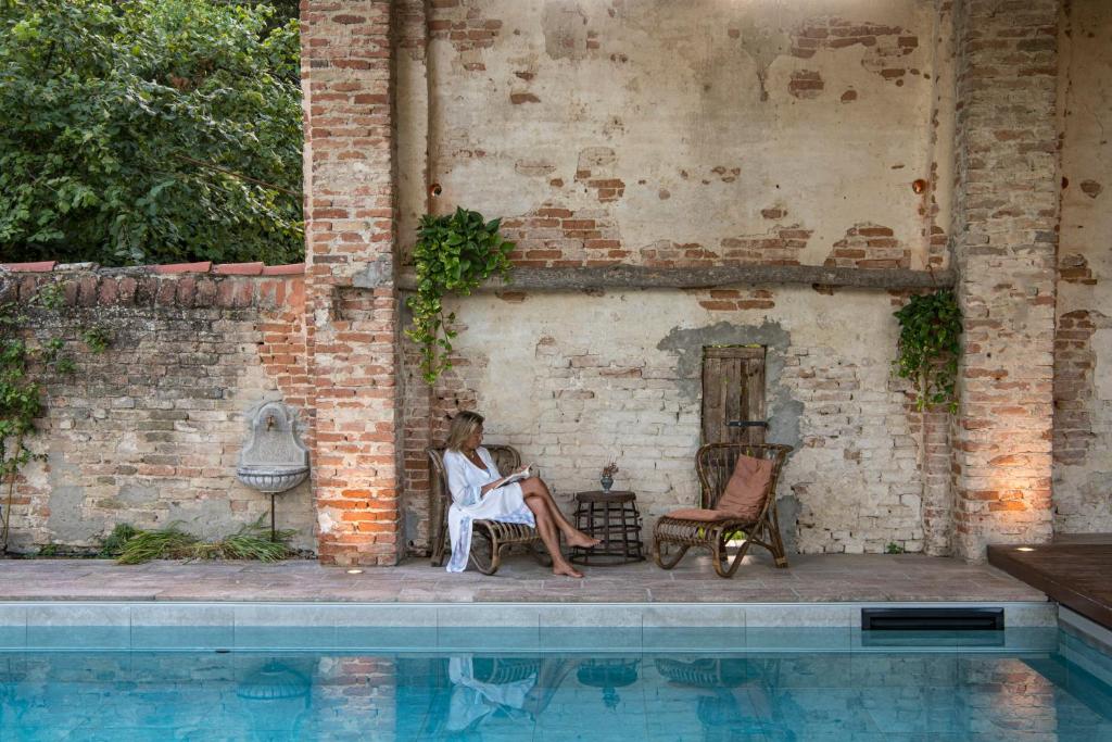 a woman sitting in a chair next to a pool at Glamping Canonici di San Marco in Mirano